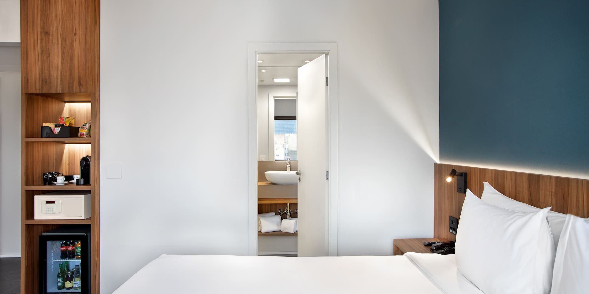 a white bed with white pillows and a blue wall