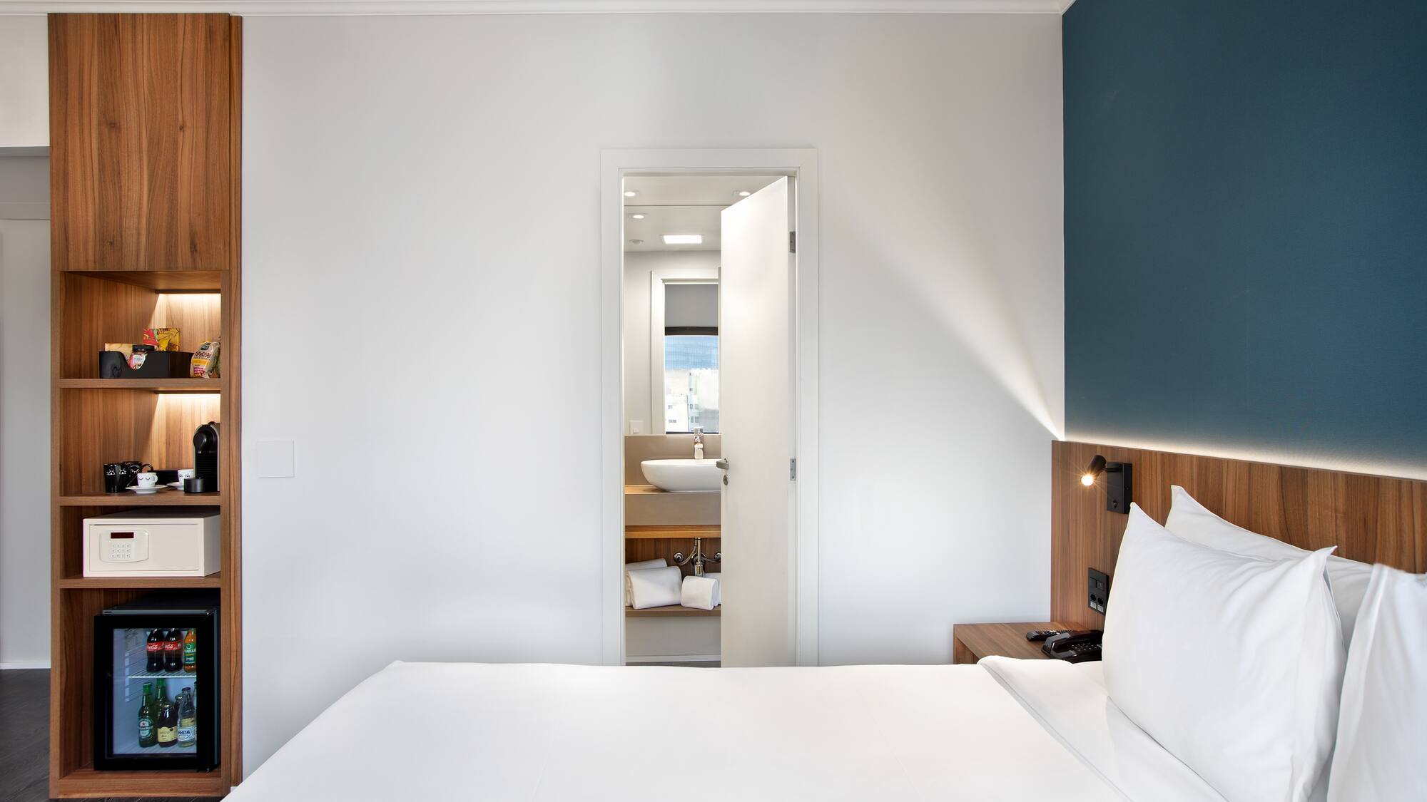 a white bed with white pillows and a blue wall