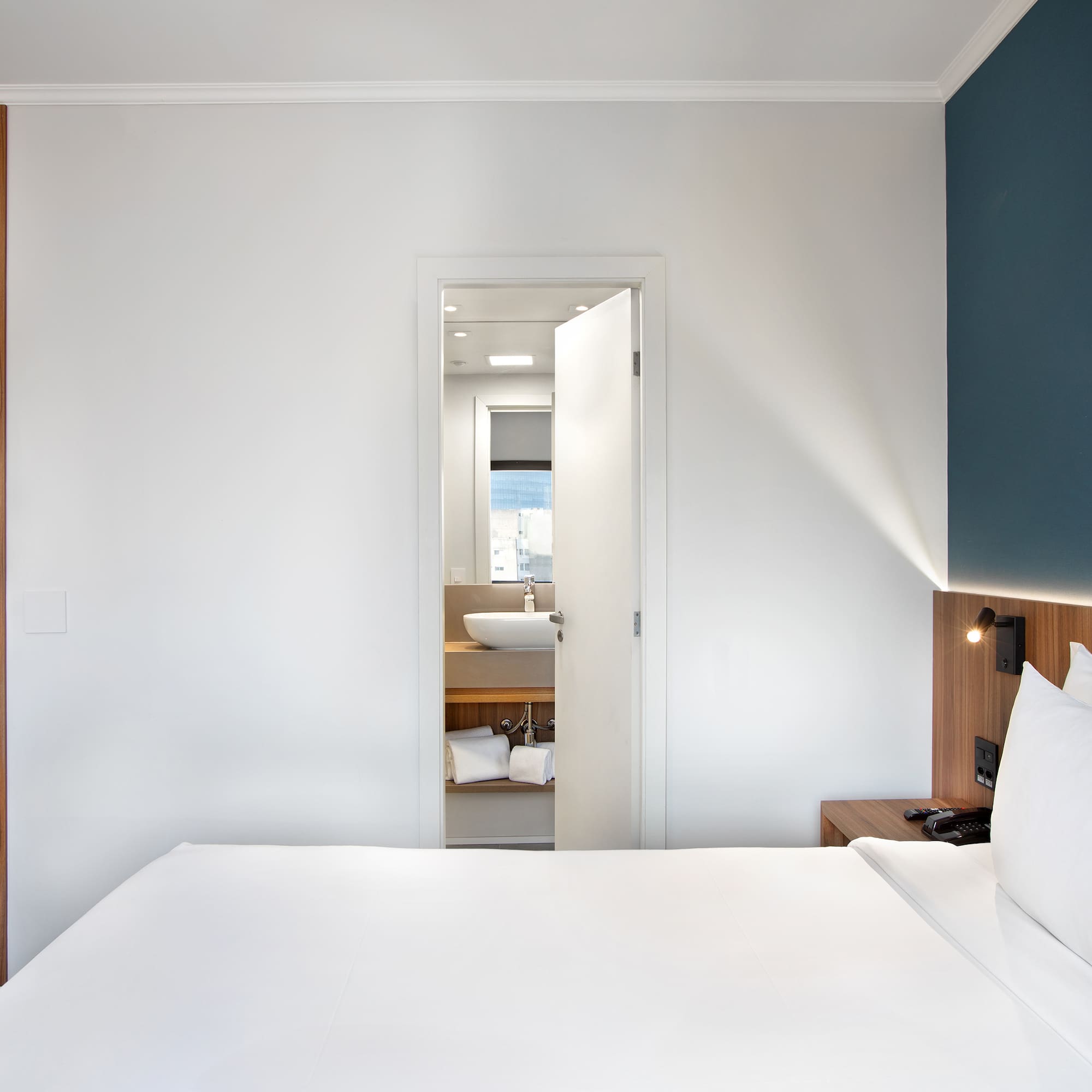 a white bed with white pillows and a blue wall