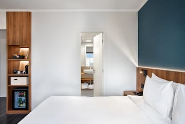 a white bed with white pillows and a blue wall