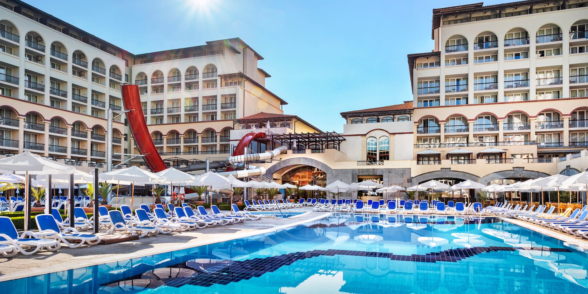 a swimming pool with a slide and chairs