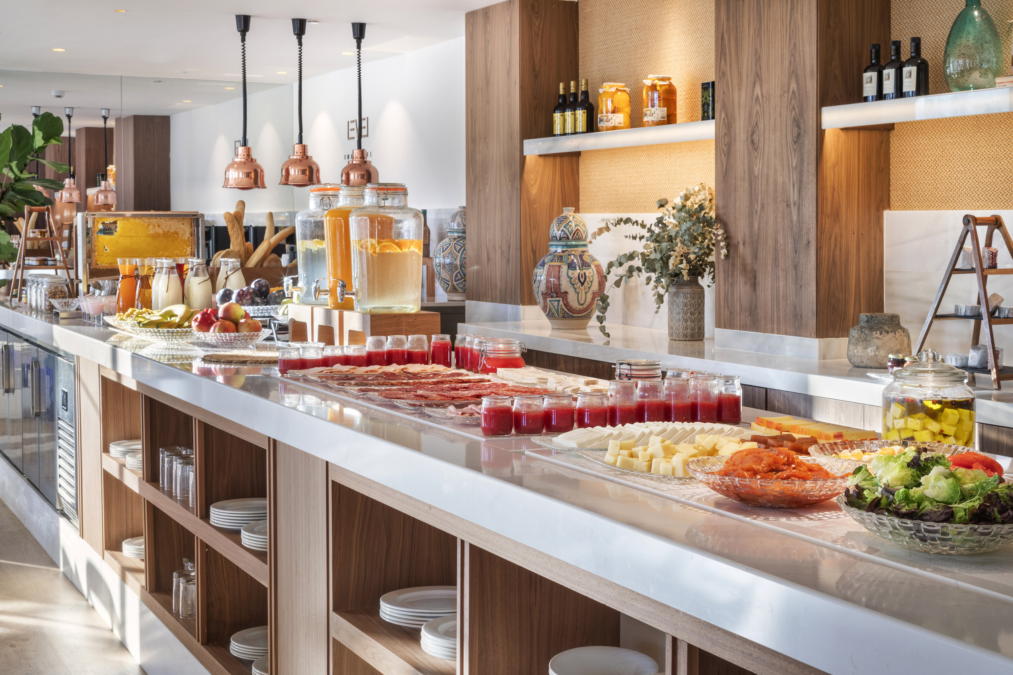 Modern breakfast buffet with fresh fruit, juices, cheeses, and cold cuts.