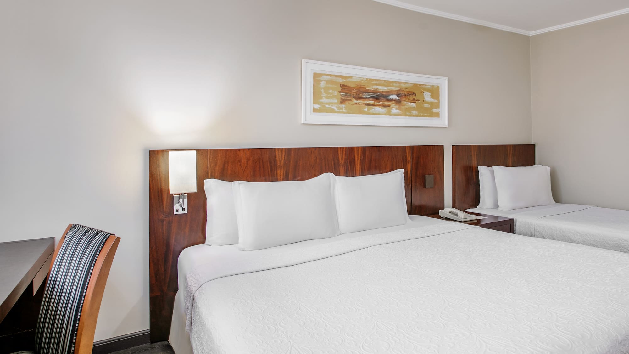 a bed with white sheets and a wood headboard