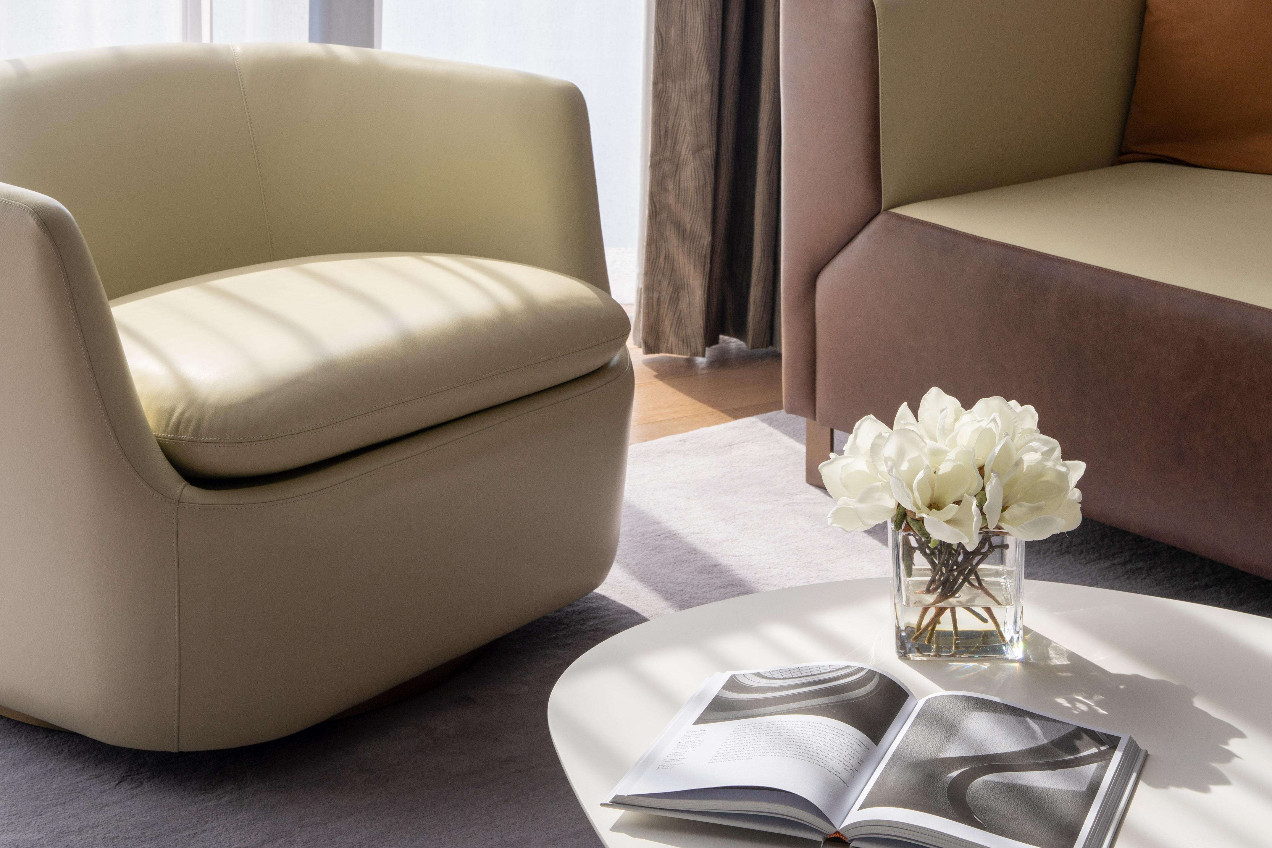 Modern living room with beige armchair, brown sofa, white coffee table, and flowers. - 1 Bedroom ME Signature Residence - ME Dubai Residences, دبي