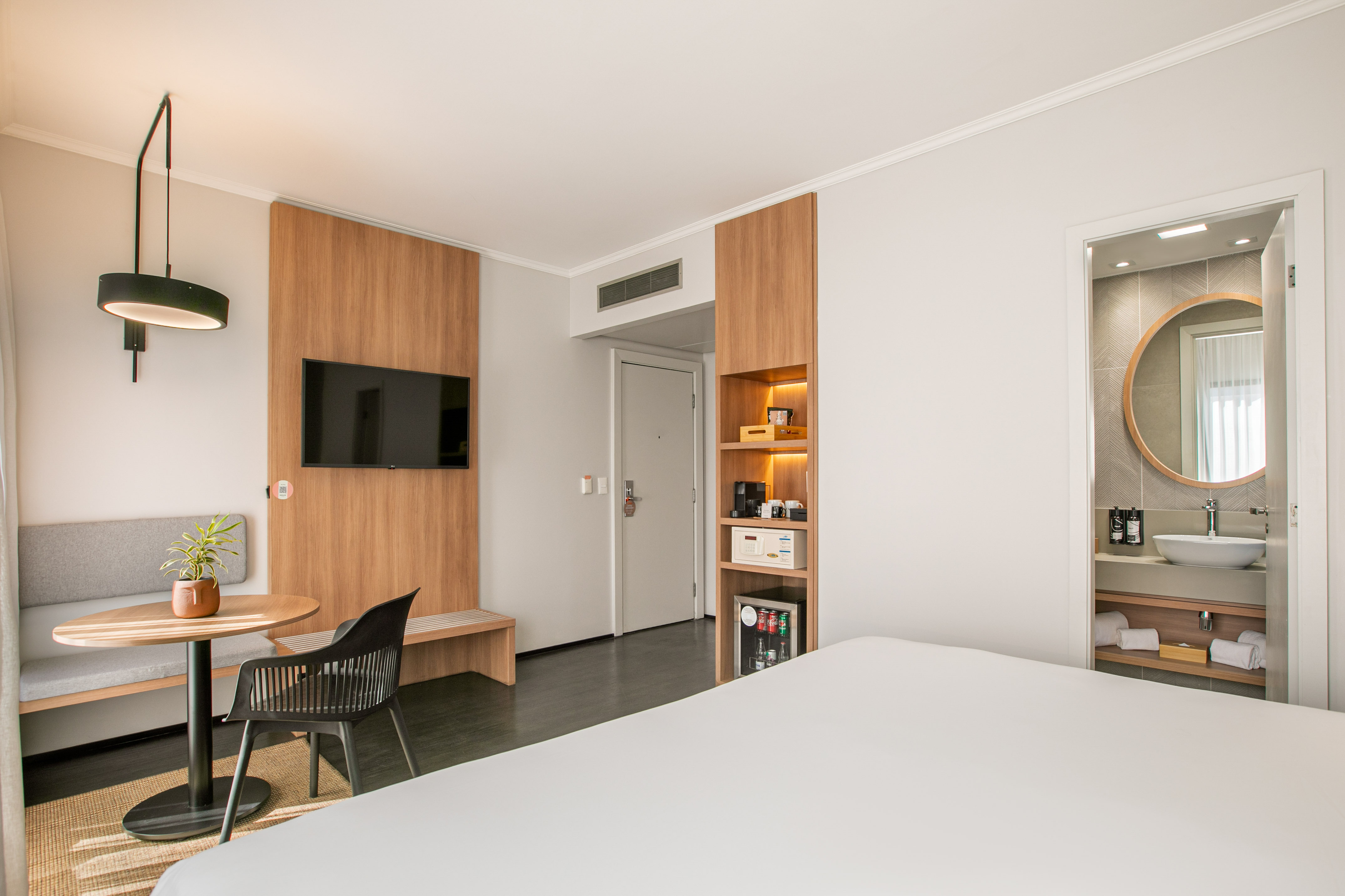 Modern room interior with TV, wood paneling, lamp, and bathroom entrance.