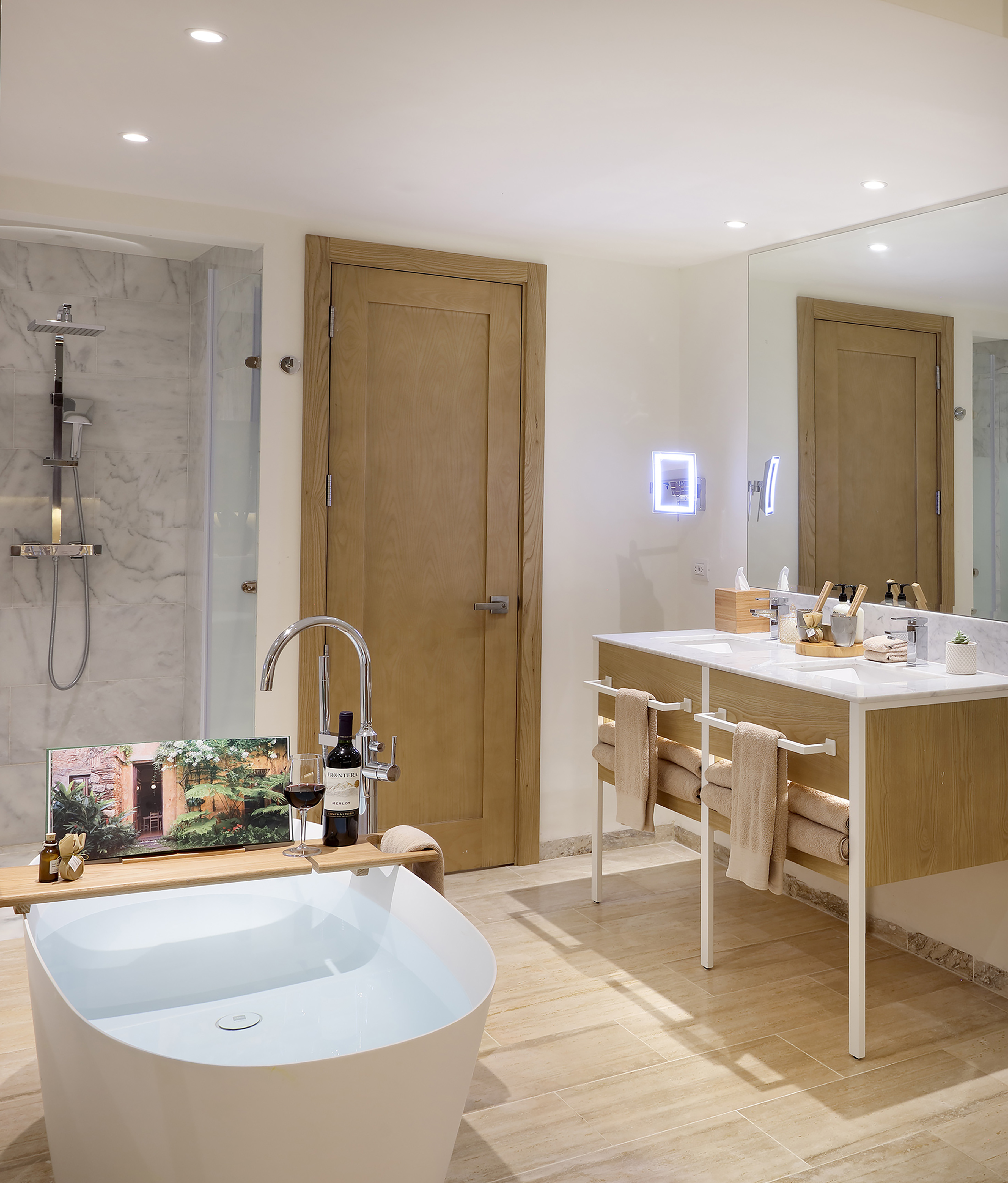 Modern bathroom with white freestanding tub, marble shower, and double vanity.