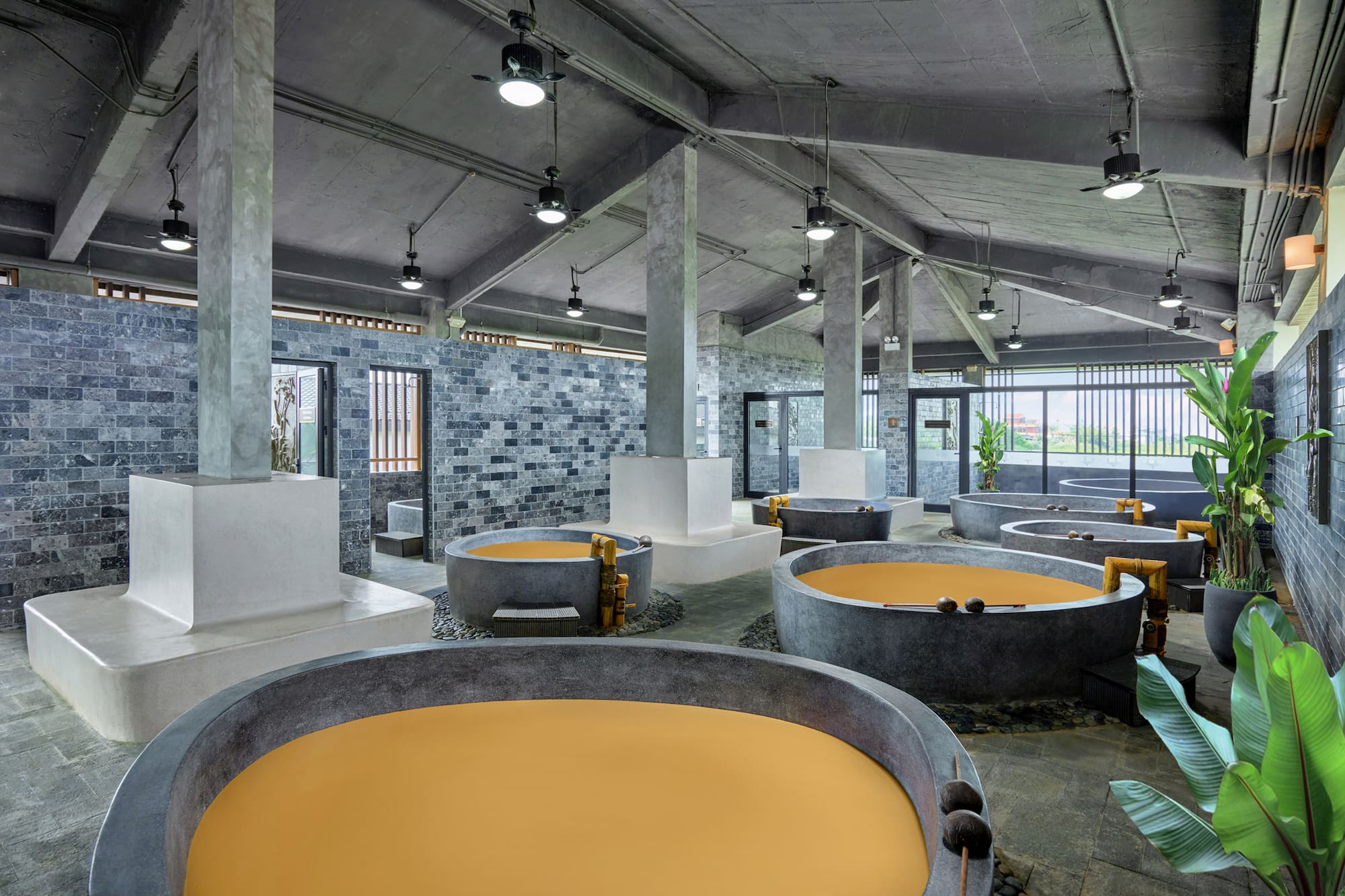 Industrial spa with multiple concrete mud bath tubs and grey brick walls.
