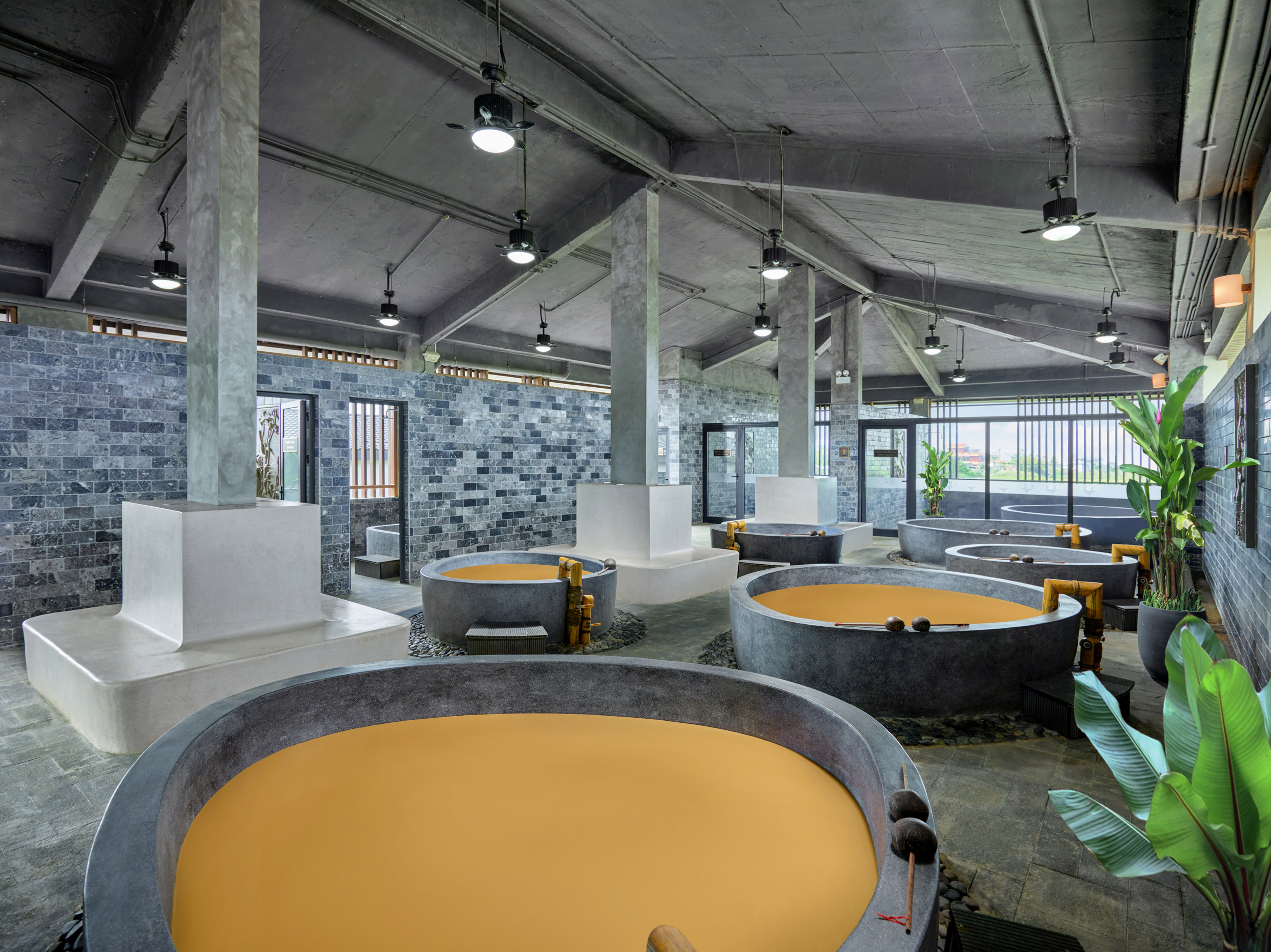 Industrial spa with multiple concrete mud bath tubs and grey brick walls.