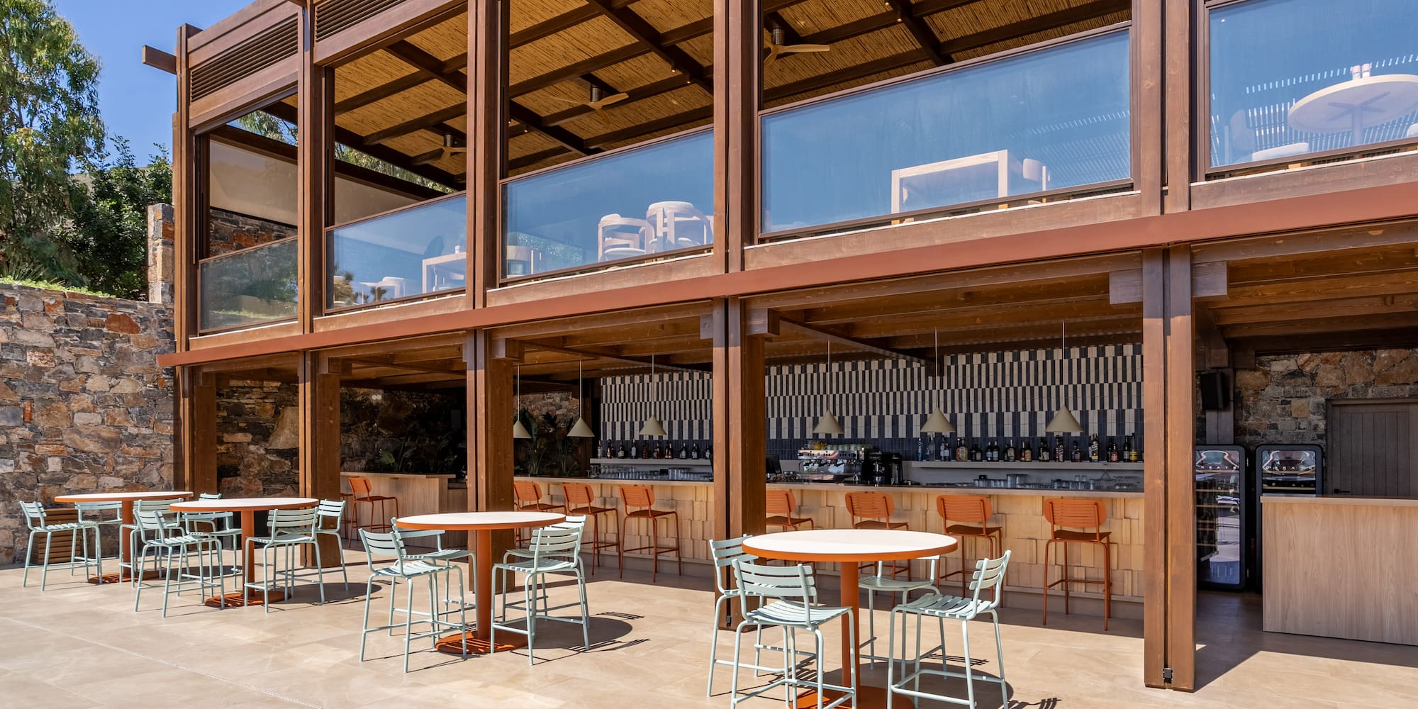 Outdoor resort bar and dining patio with modern wooden structure, straw roof.