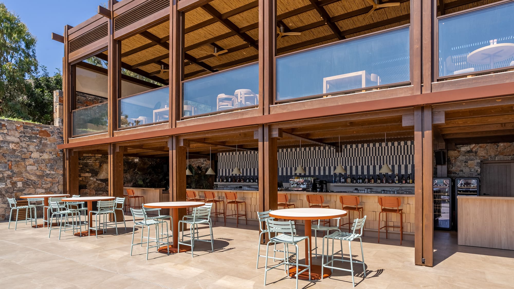 Outdoor resort bar and dining patio with modern wooden structure, straw roof.
