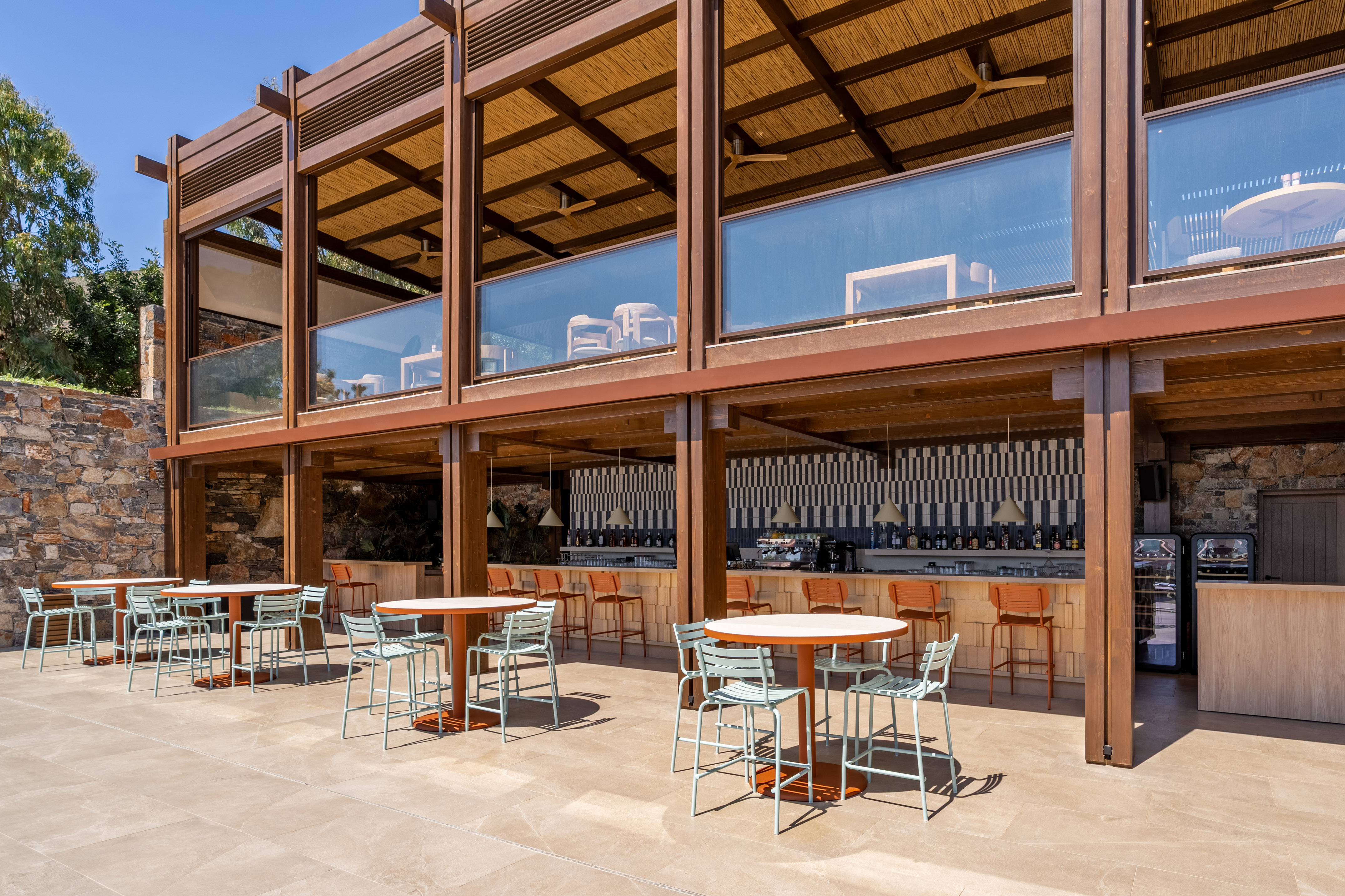 Outdoor resort bar and dining patio with modern wooden structure, straw roof.