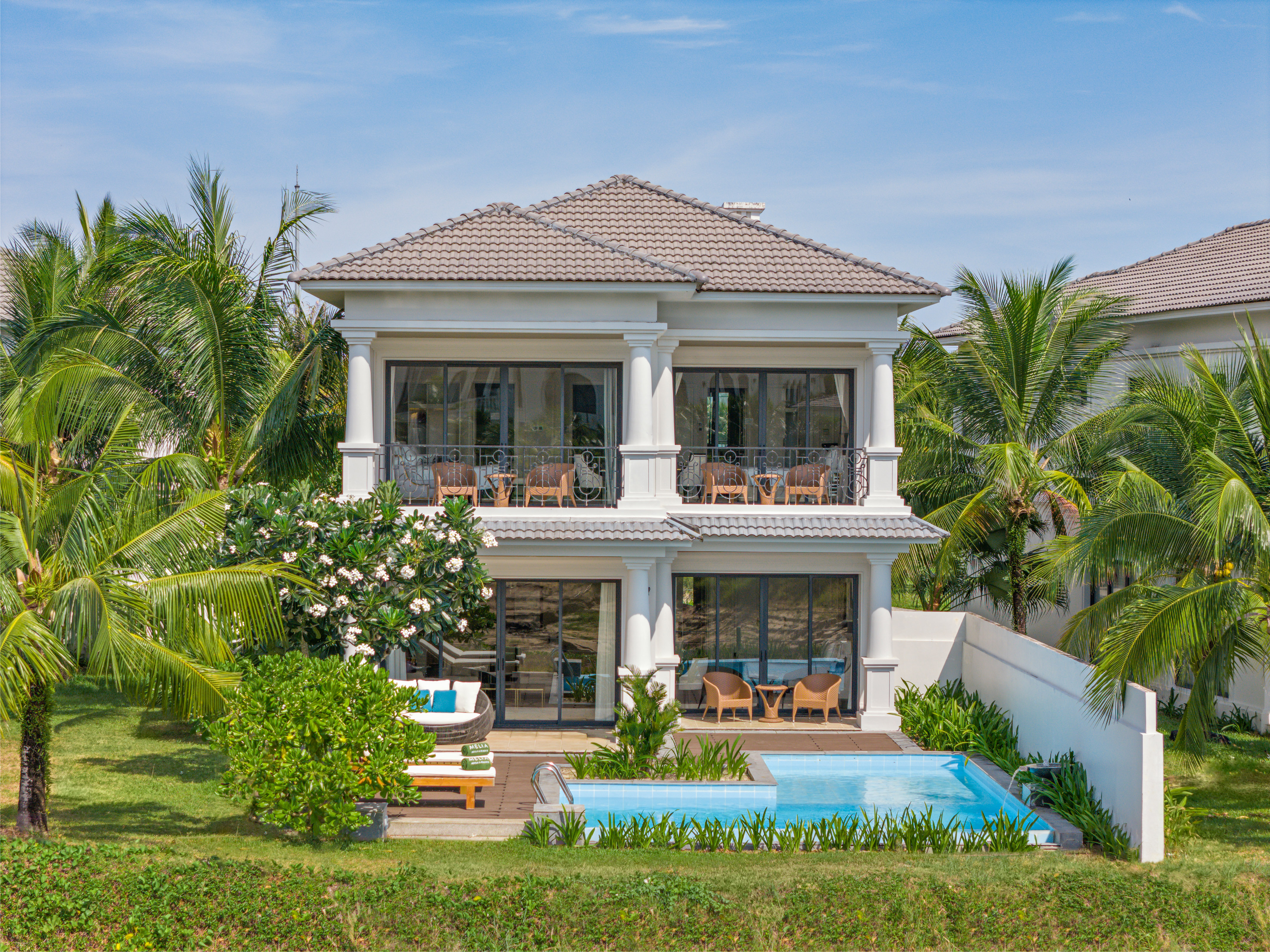 Luxury tropical villa with private pool, lush garden, and palm trees.