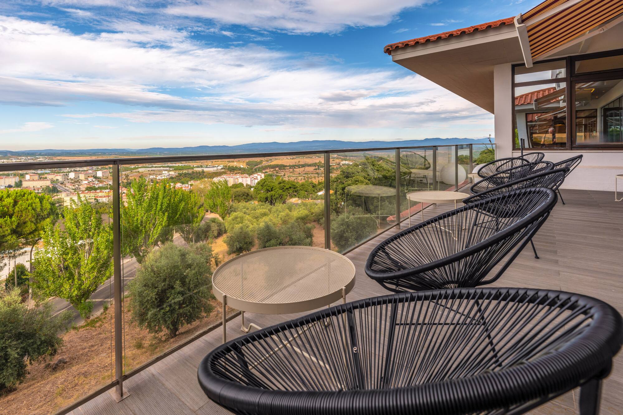 Outdoor terrace with modern black chairs, tables, and panoramic city views.