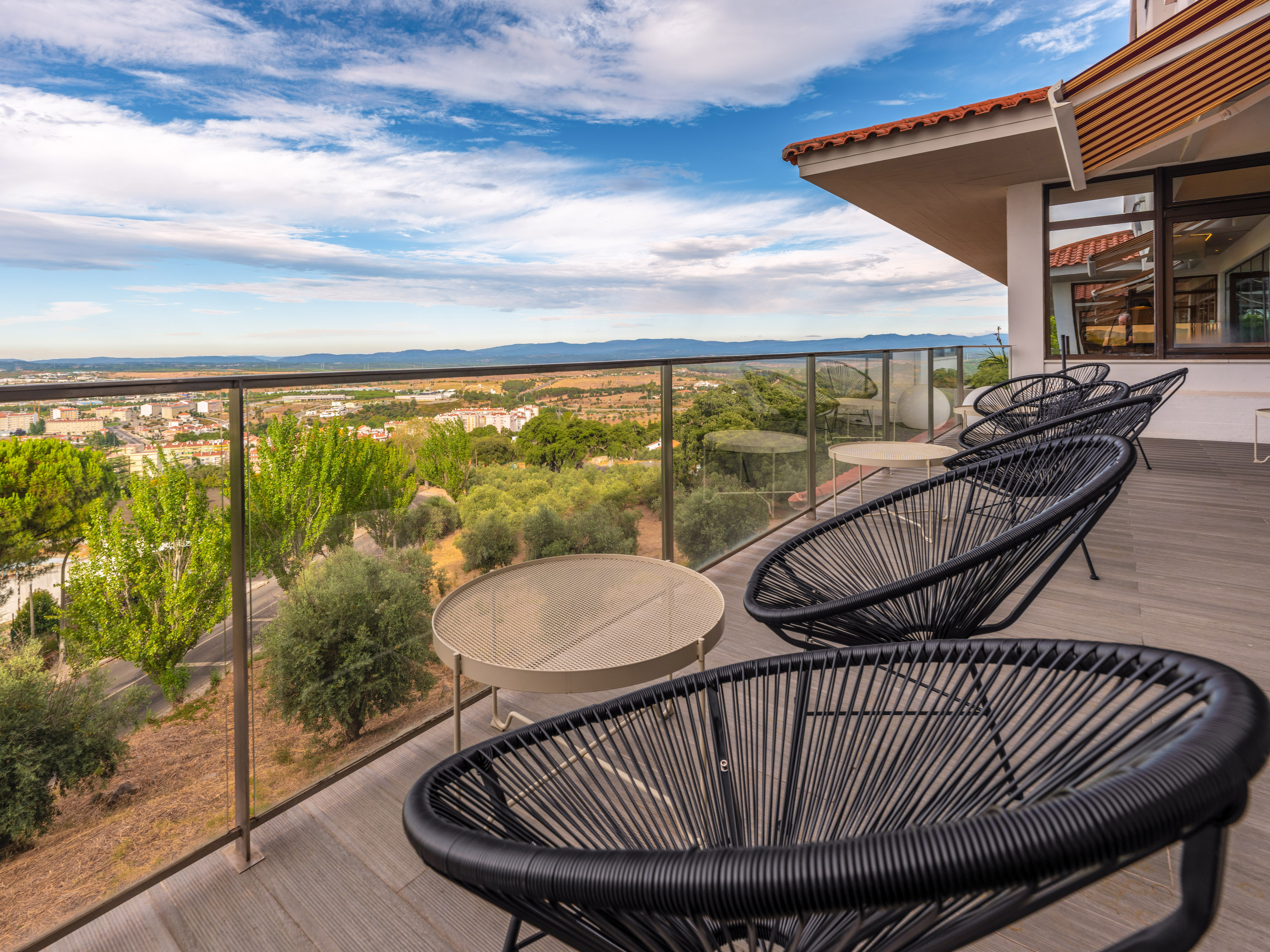 Outdoor terrace with modern black chairs, tables, and panoramic city views.