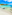 White sand beach with clear turquoise water, lush green coastline, blue sky.