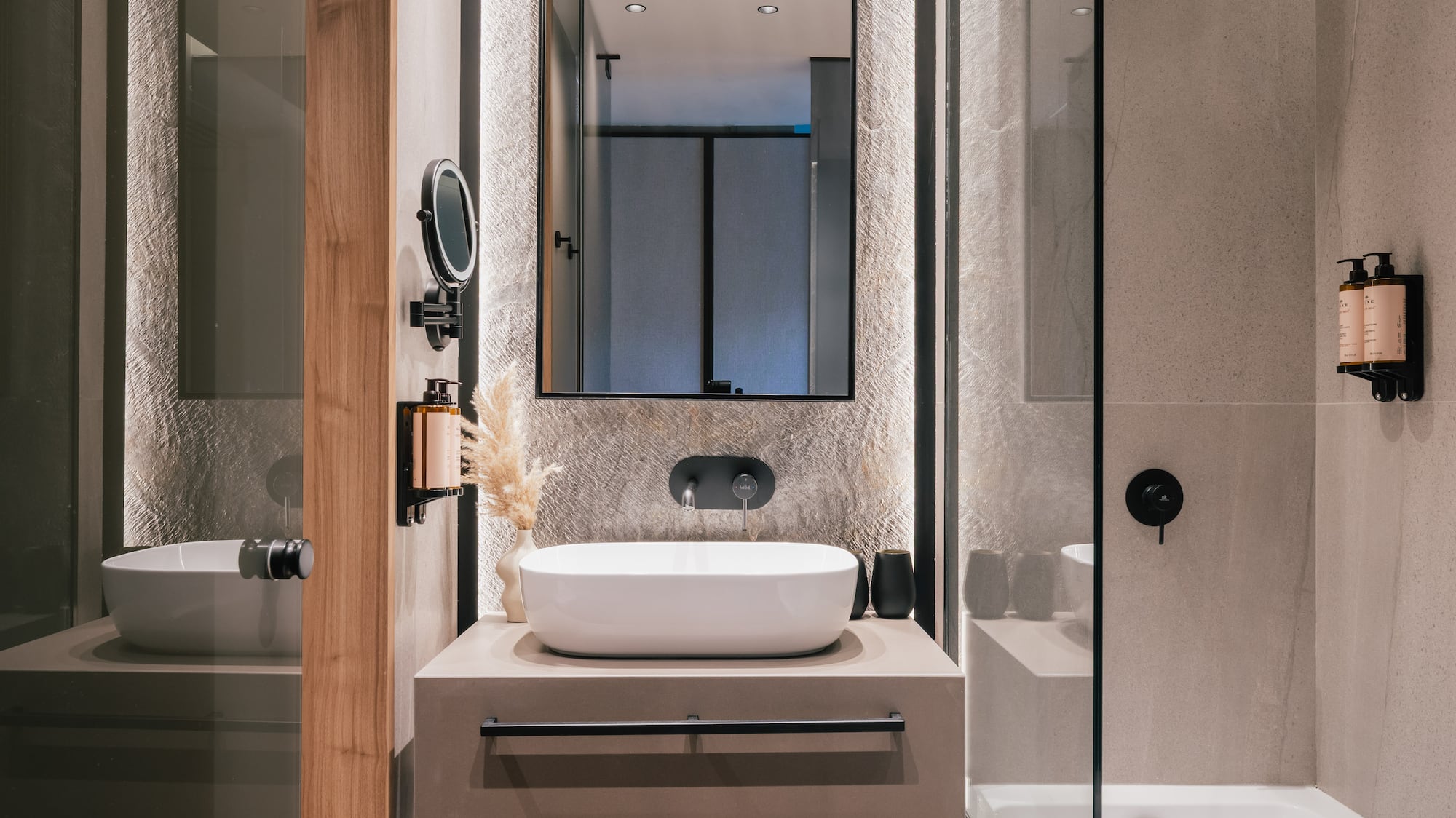Modern bathroom with sleek vanity, vessel sink, textured wall, and bathtub shower.
