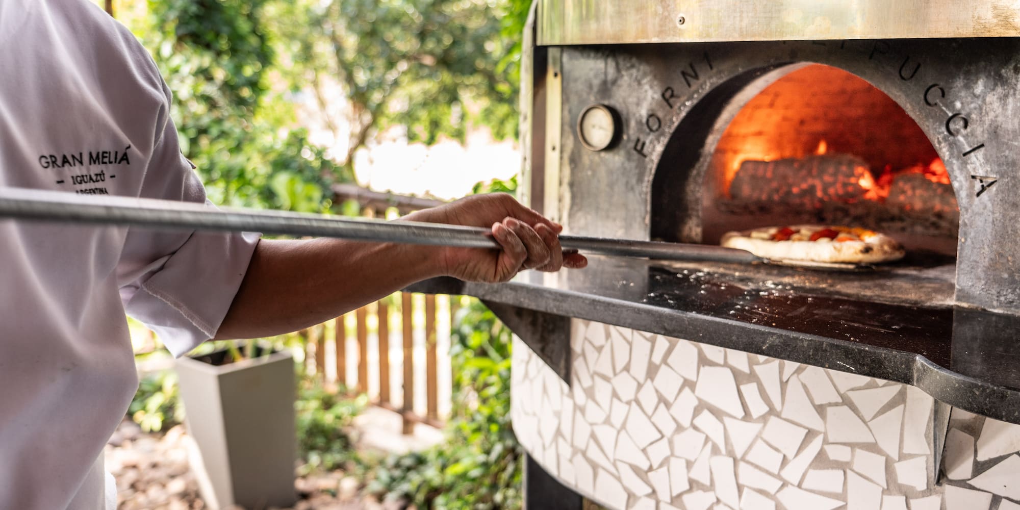 a person holding a stick over a pizza oven