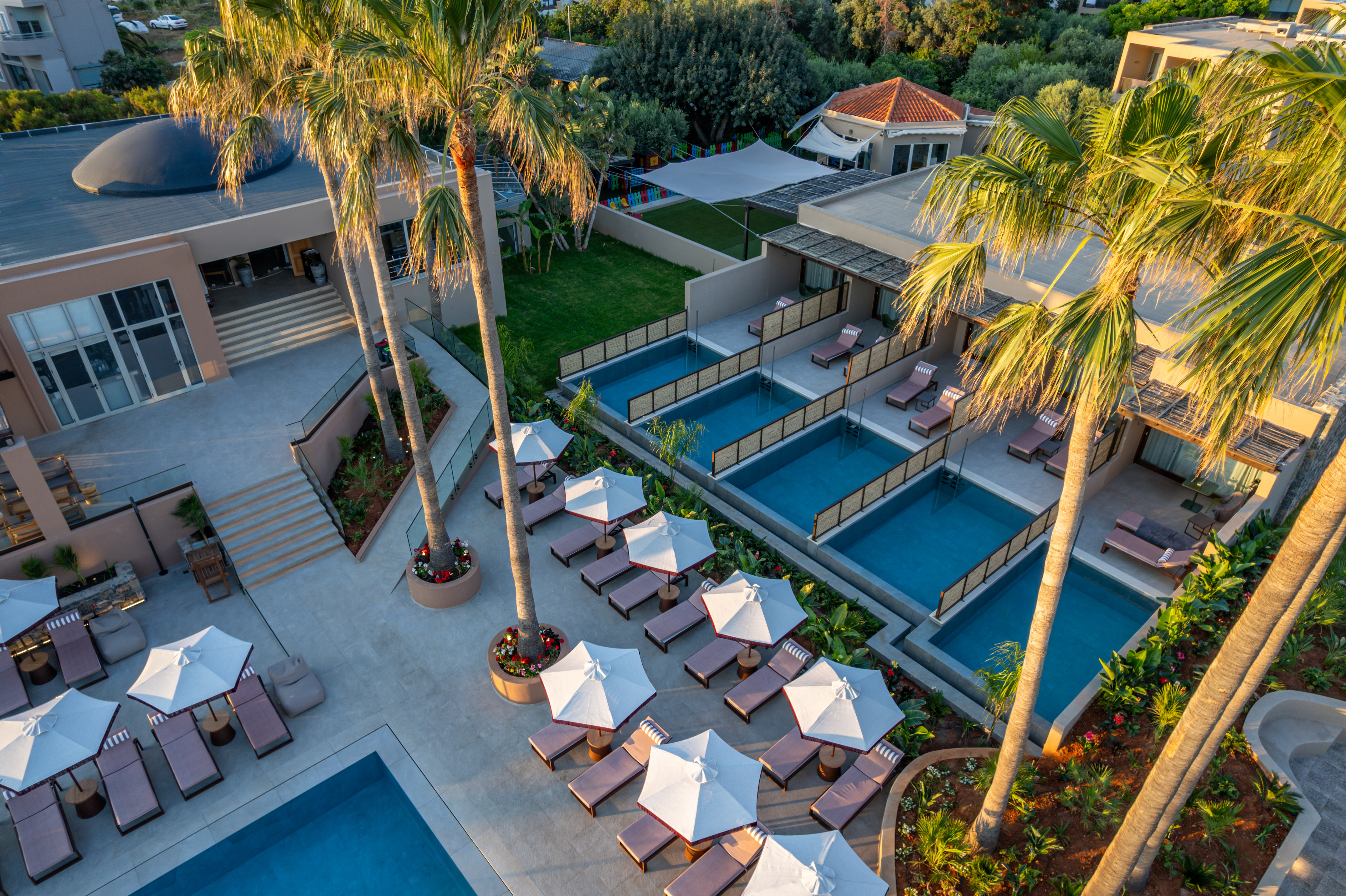 Aerial view: luxury hotel with multiple pools, palm trees, and sun loungers.
