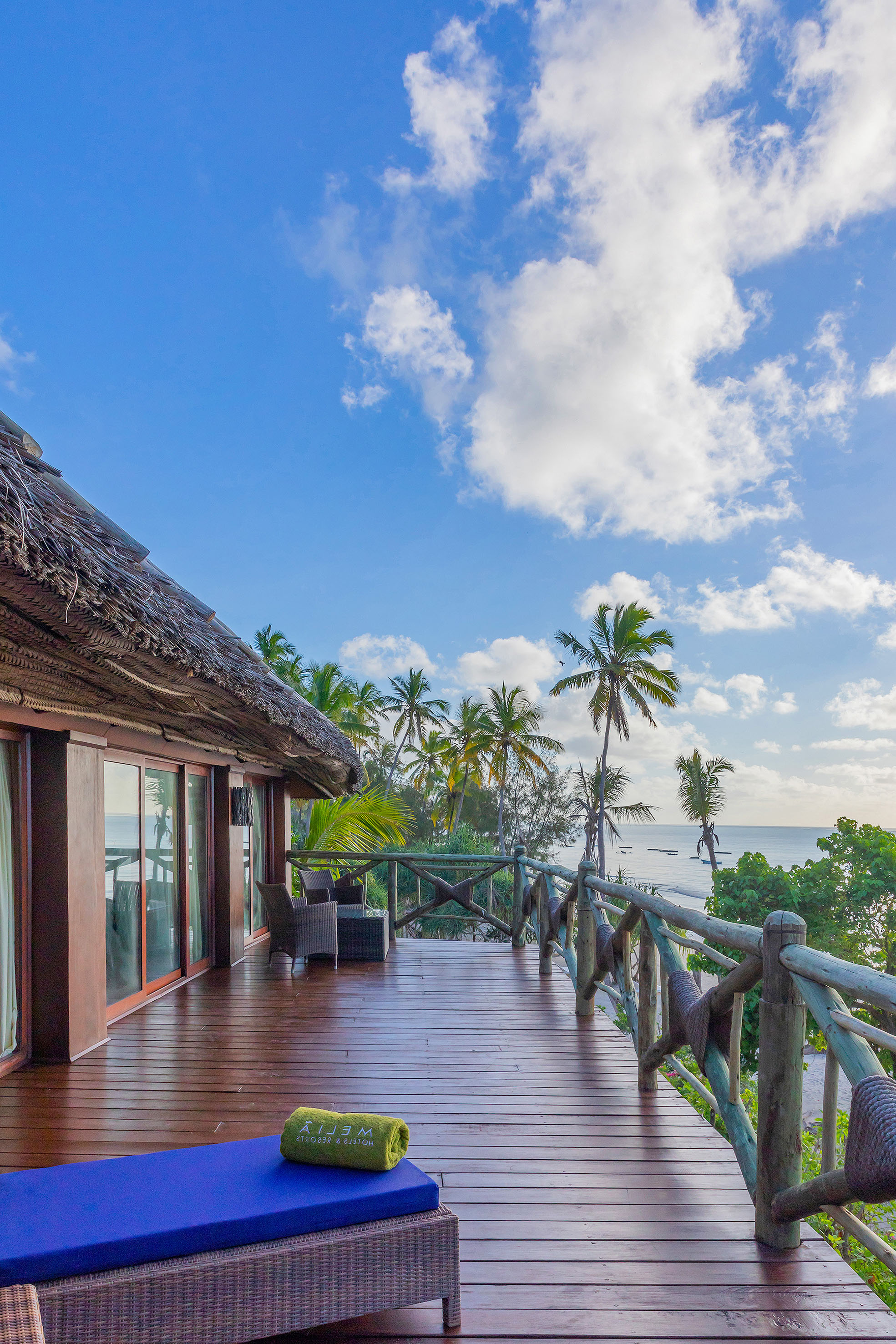 a deck with a thatched roof and palm trees