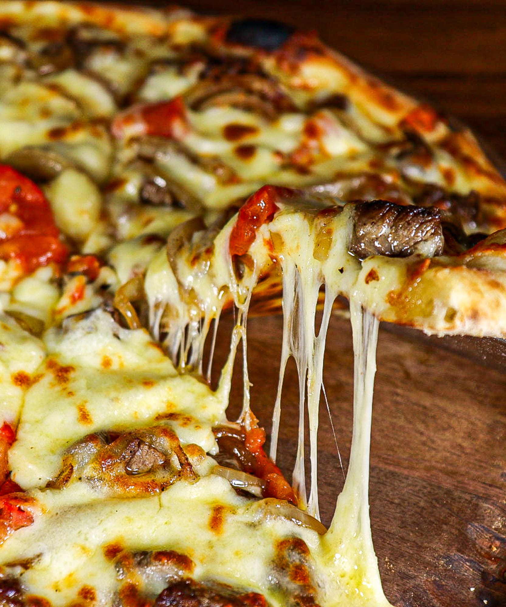a pizza with cheese and mushrooms on a wooden plate