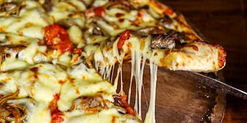 a pizza with cheese and mushrooms on a wooden plate