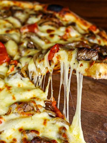 a pizza with cheese and mushrooms on a wooden plate