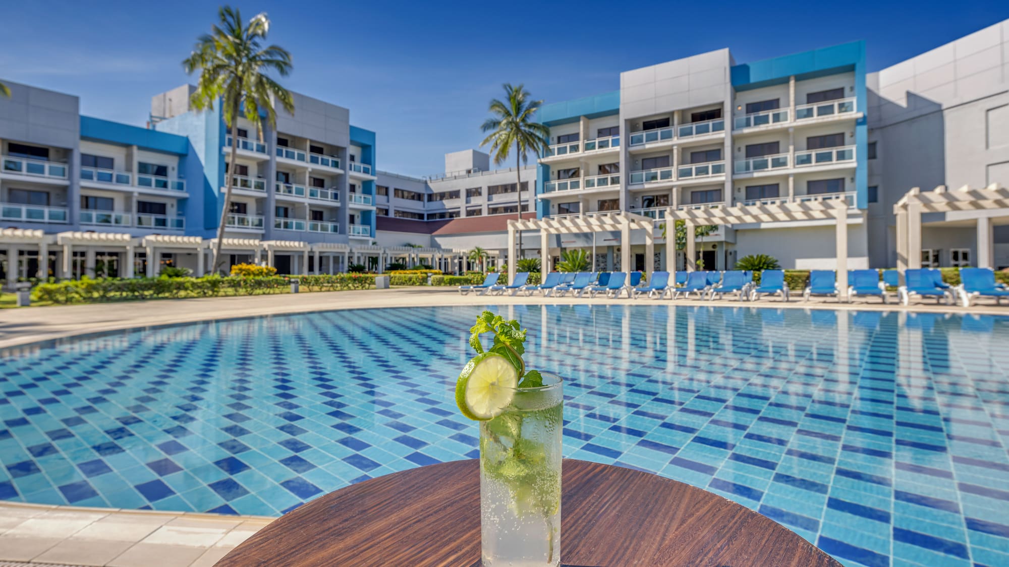 a glass of drink on a table next to a pool