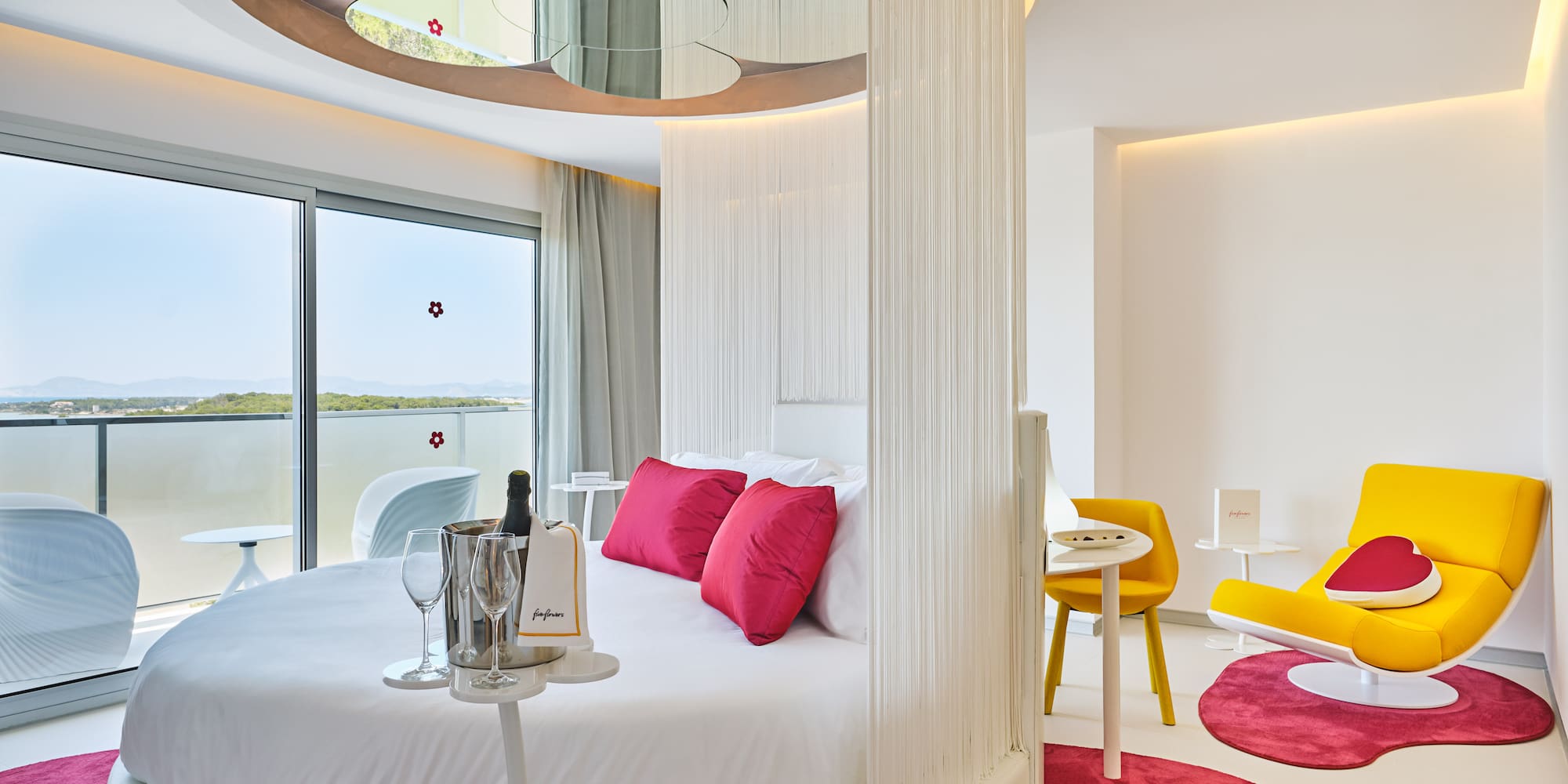 Modern luxury hotel room with round bed, ocean view, and champagne.