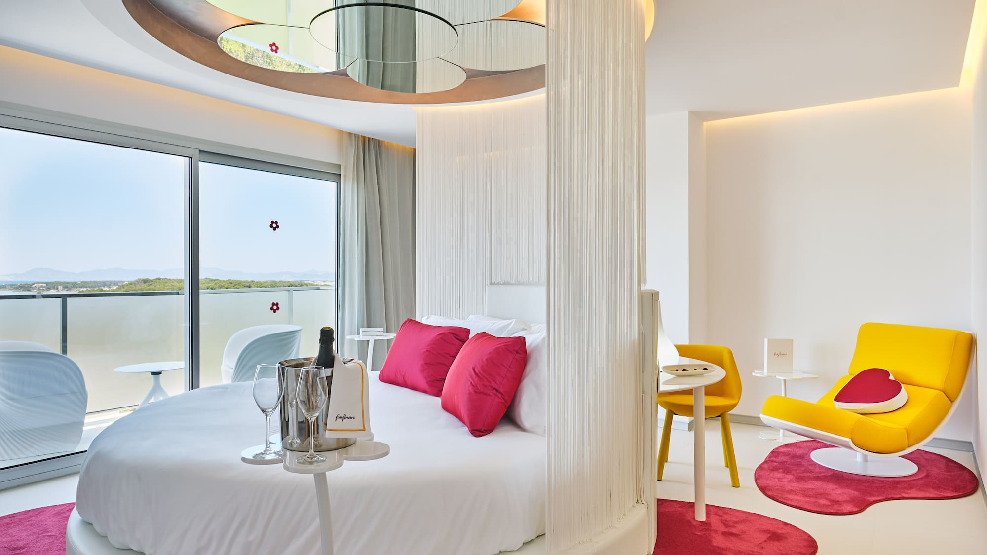 Modern luxury hotel room with round bed, ocean view, and champagne.