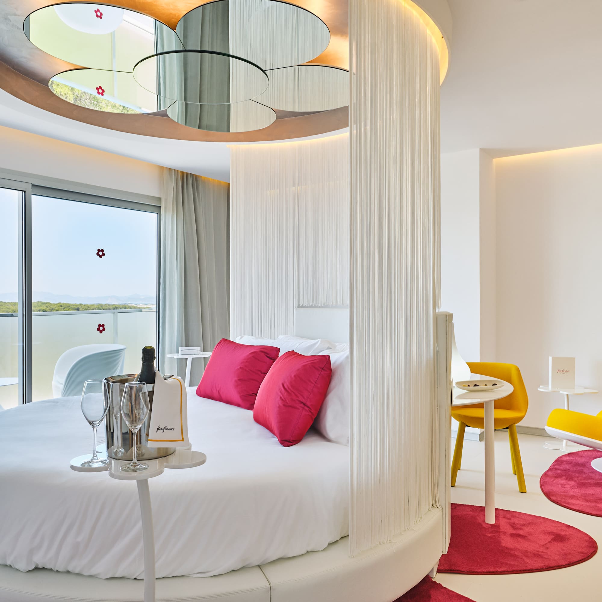 Modern luxury hotel room with round bed, ocean view, and champagne.