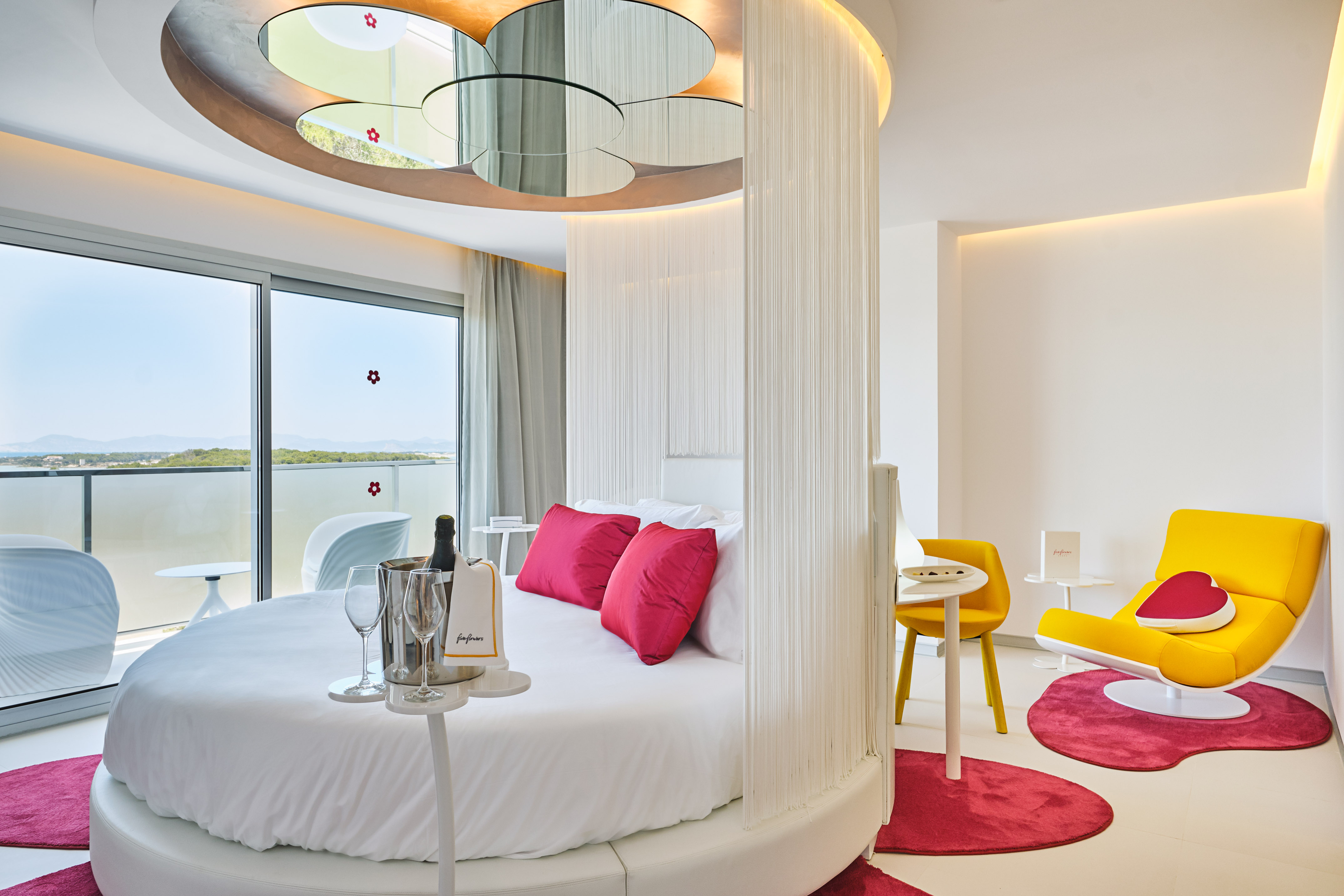 Modern luxury hotel room with round bed, ocean view, and champagne.