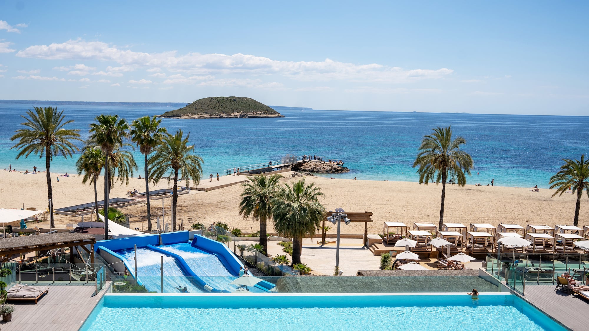 a pool with water slides and palm trees on a beach