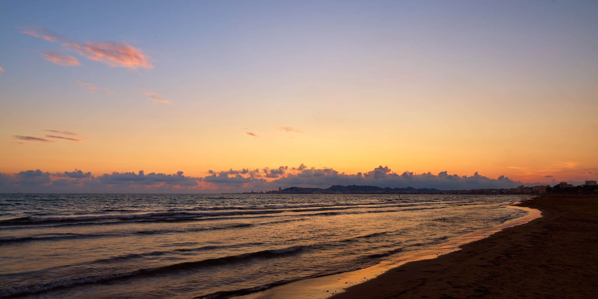 a beach with waves and a sunset