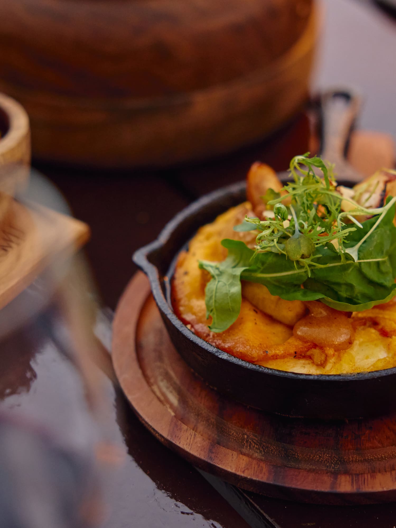 Empanada, gratinado de papas con rúcula fresca y salsa, en mesa rústica.