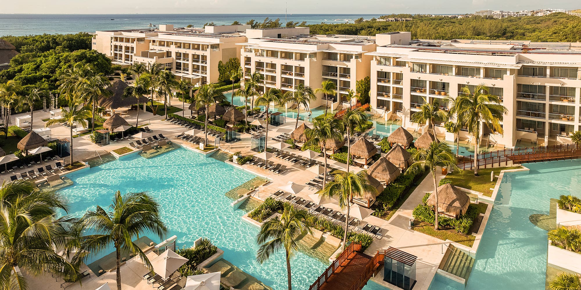 Luxury beachfront resort with pools, palm trees, cabanas, and ocean.