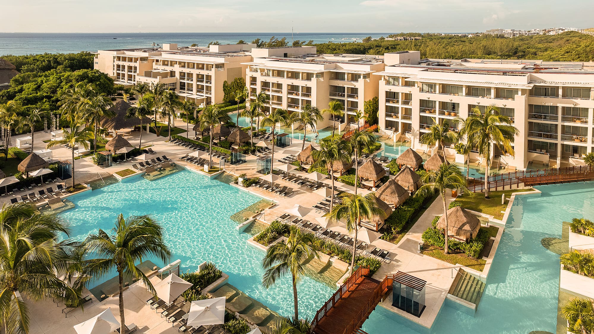Luxury beachfront resort with pools, palm trees, cabanas, and ocean.