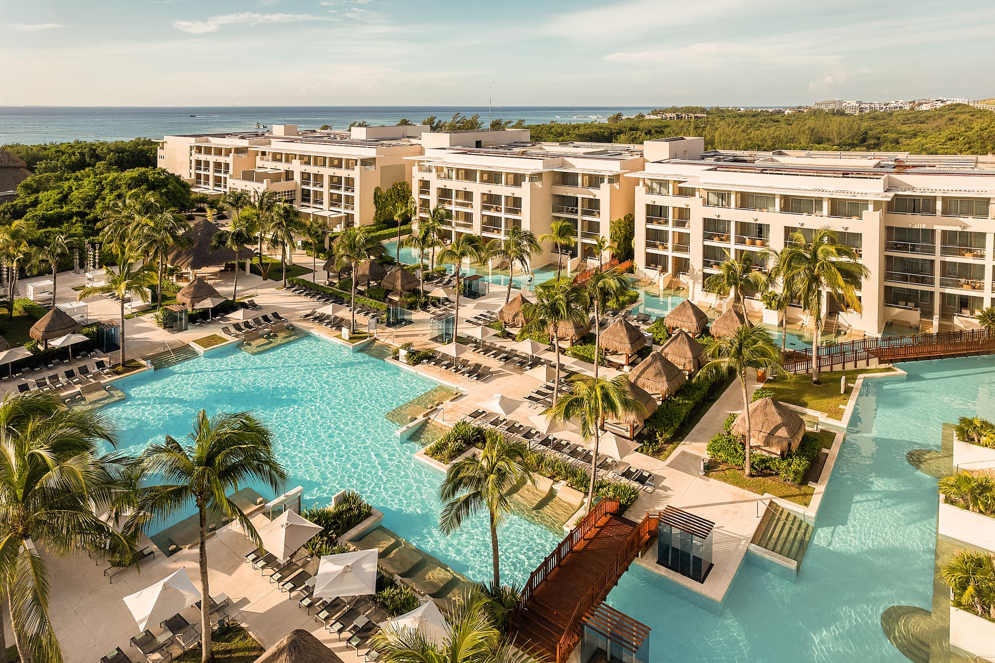Luxury beachfront resort with pools, palm trees, cabanas, and ocean.