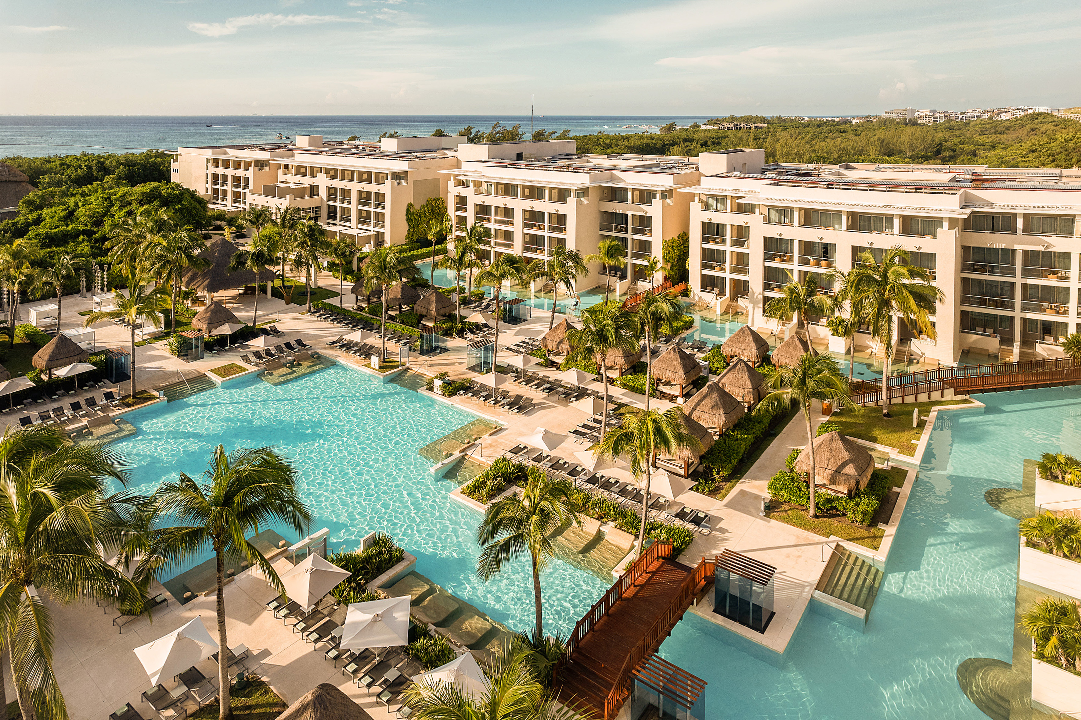 Luxury beachfront resort with pools, palm trees, cabanas, and ocean.