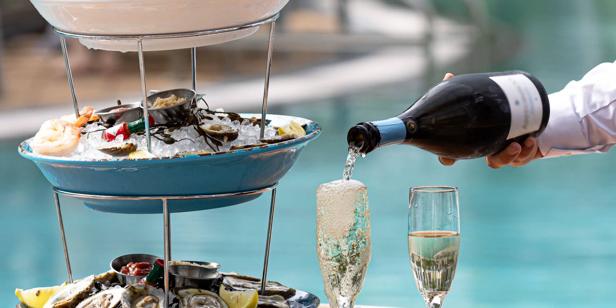 a person pouring champagne into a three tiered tray of food