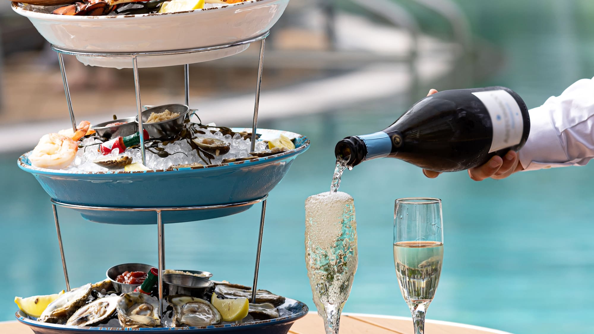a person pouring champagne into a three tiered tray of food