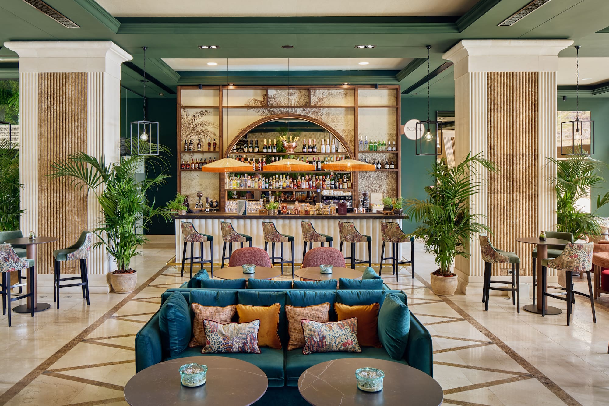 Luxurious hotel lobby bar with tropical decor, green walls, and plush seating.