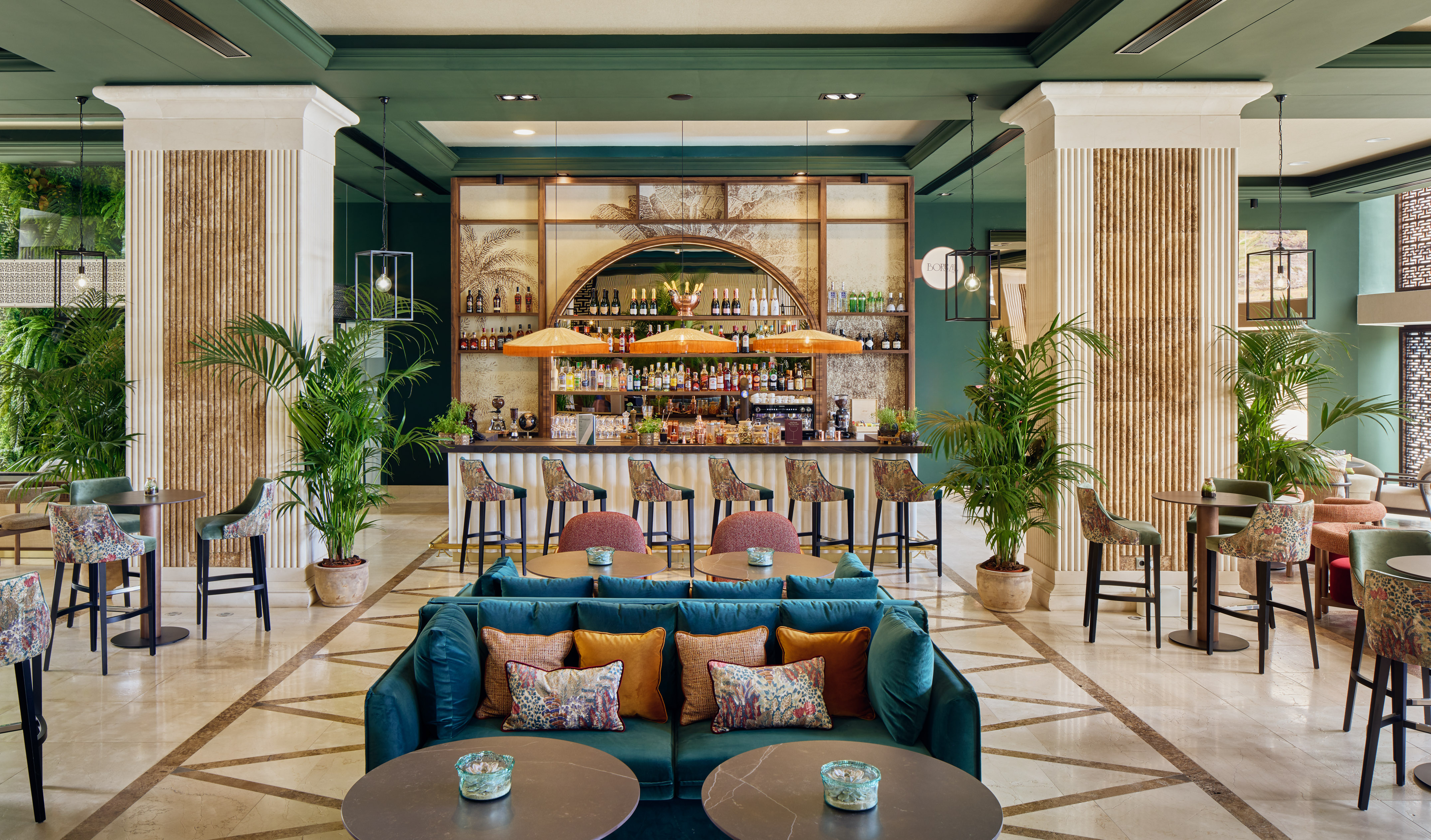 Luxurious hotel lobby bar with tropical decor, green walls, and plush seating.