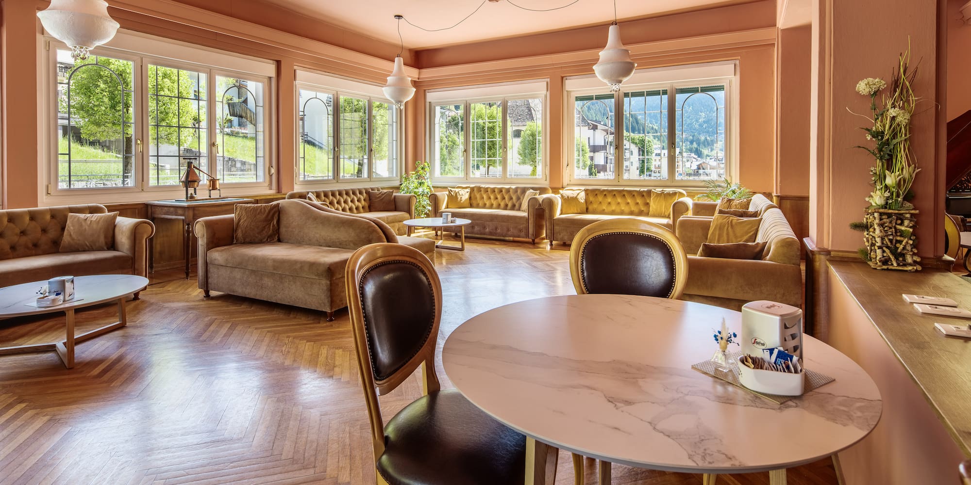 Elegant hotel lounge with salmon walls, velvet seating, and parquet floor.