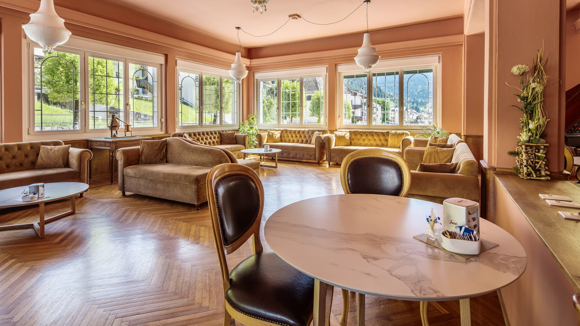 Elegant hotel lounge with salmon walls, velvet seating, and parquet floor.