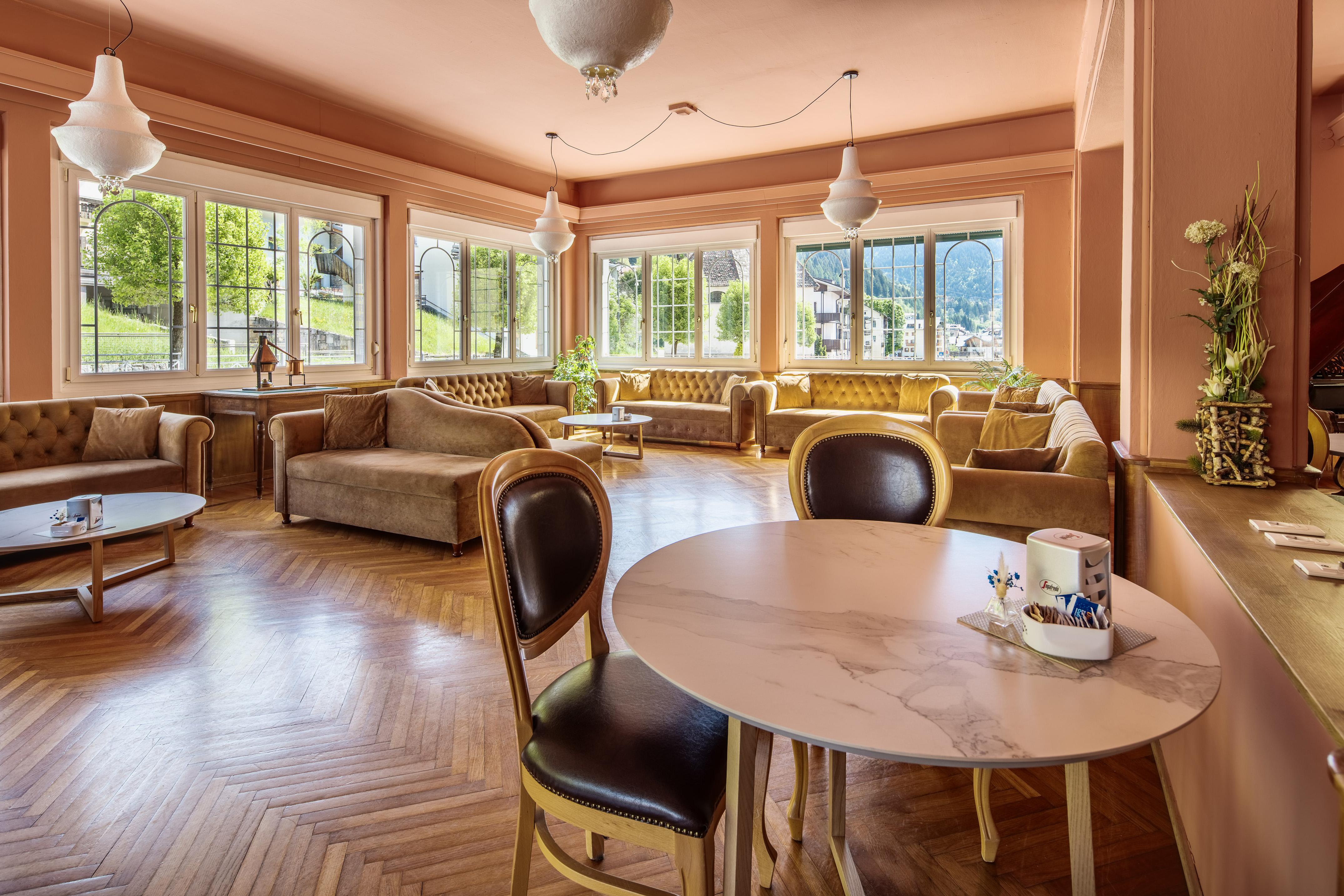 Elegant hotel lounge with salmon walls, velvet seating, and parquet floor.