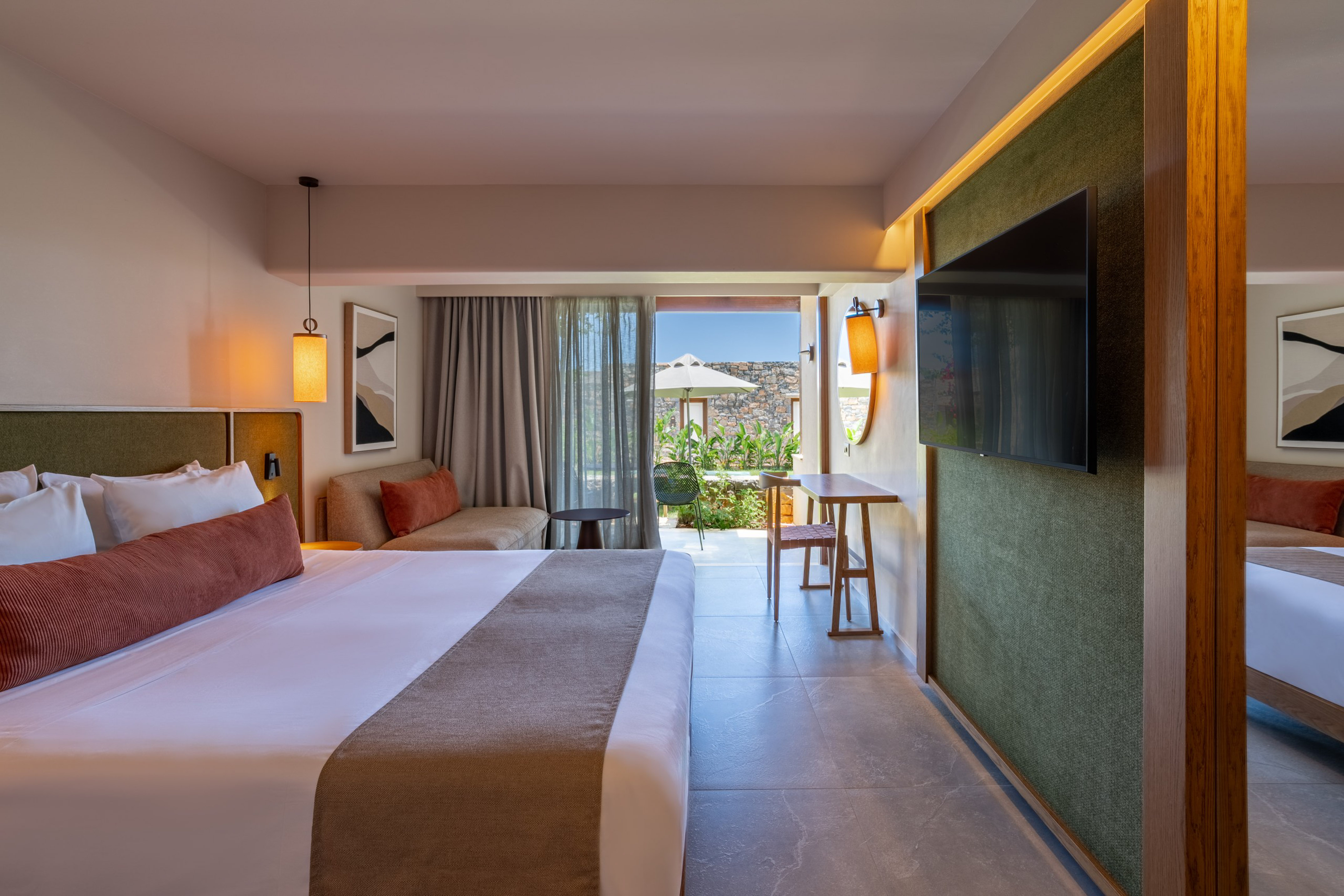 Modern luxury hotel room with king bed, sofa, TV, and private outdoor terrace.
