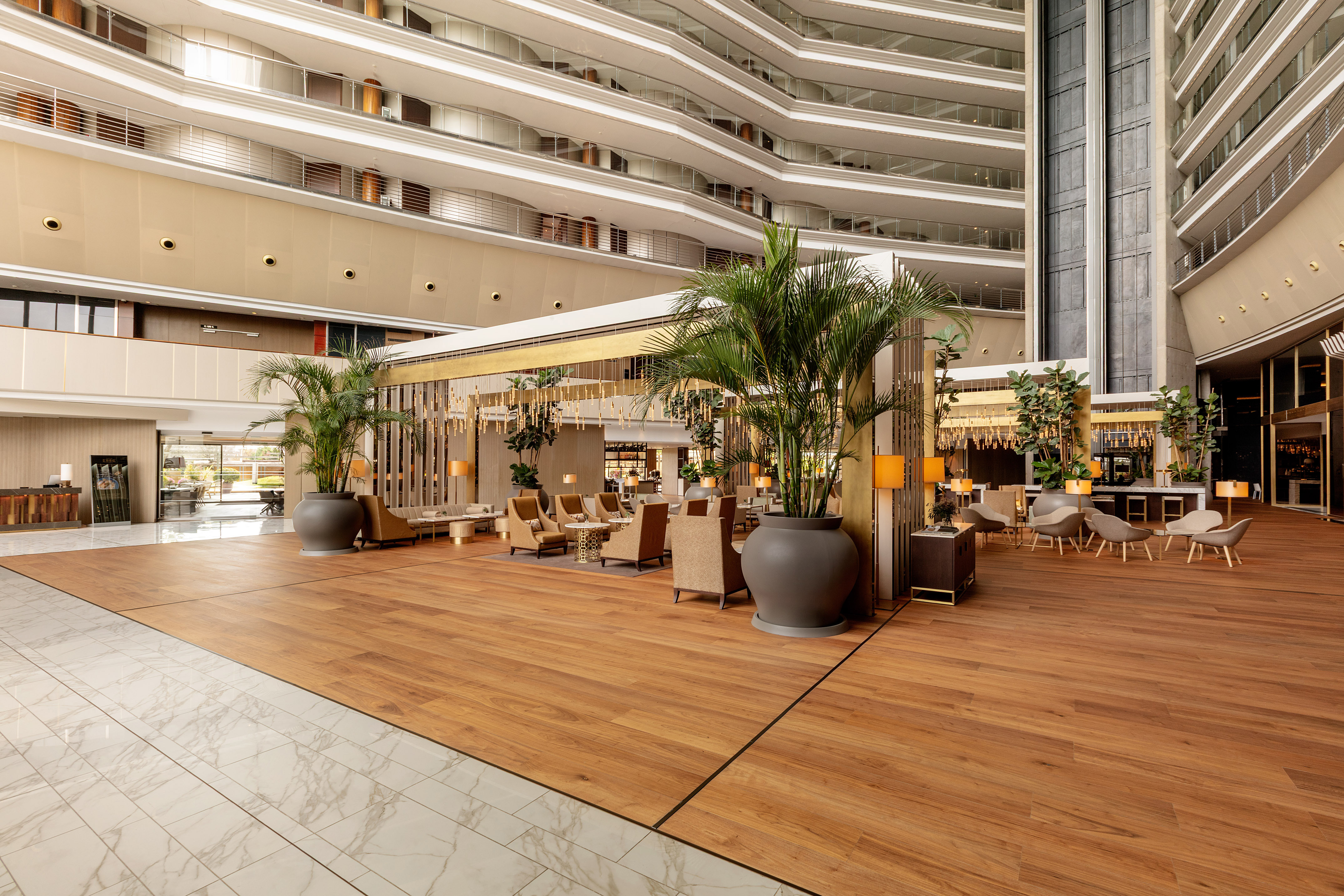 Grand modern hotel lobby with multi-story atrium, lounge seating, and wood floors.