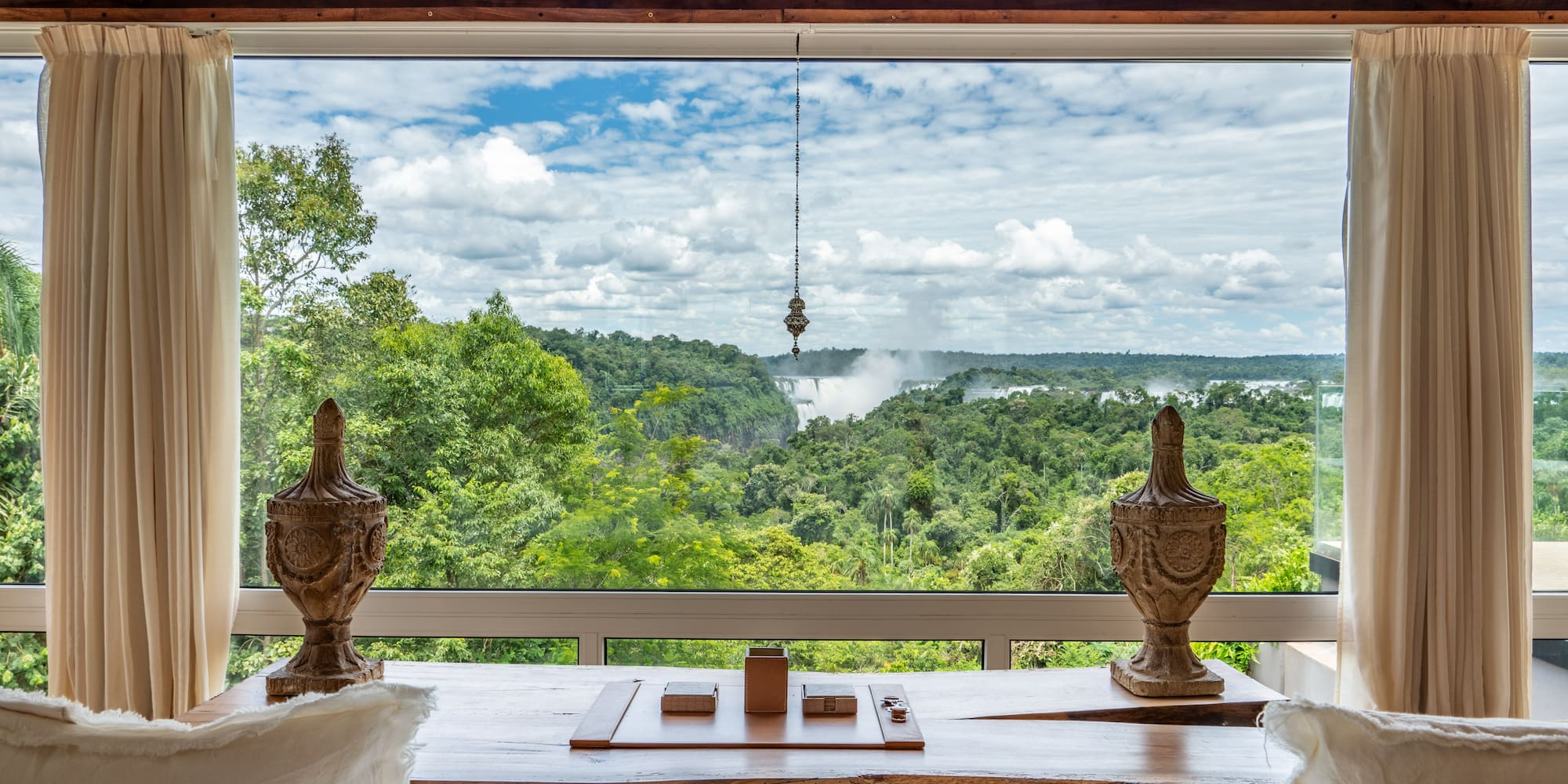 a room with a view of a forest and a waterfall