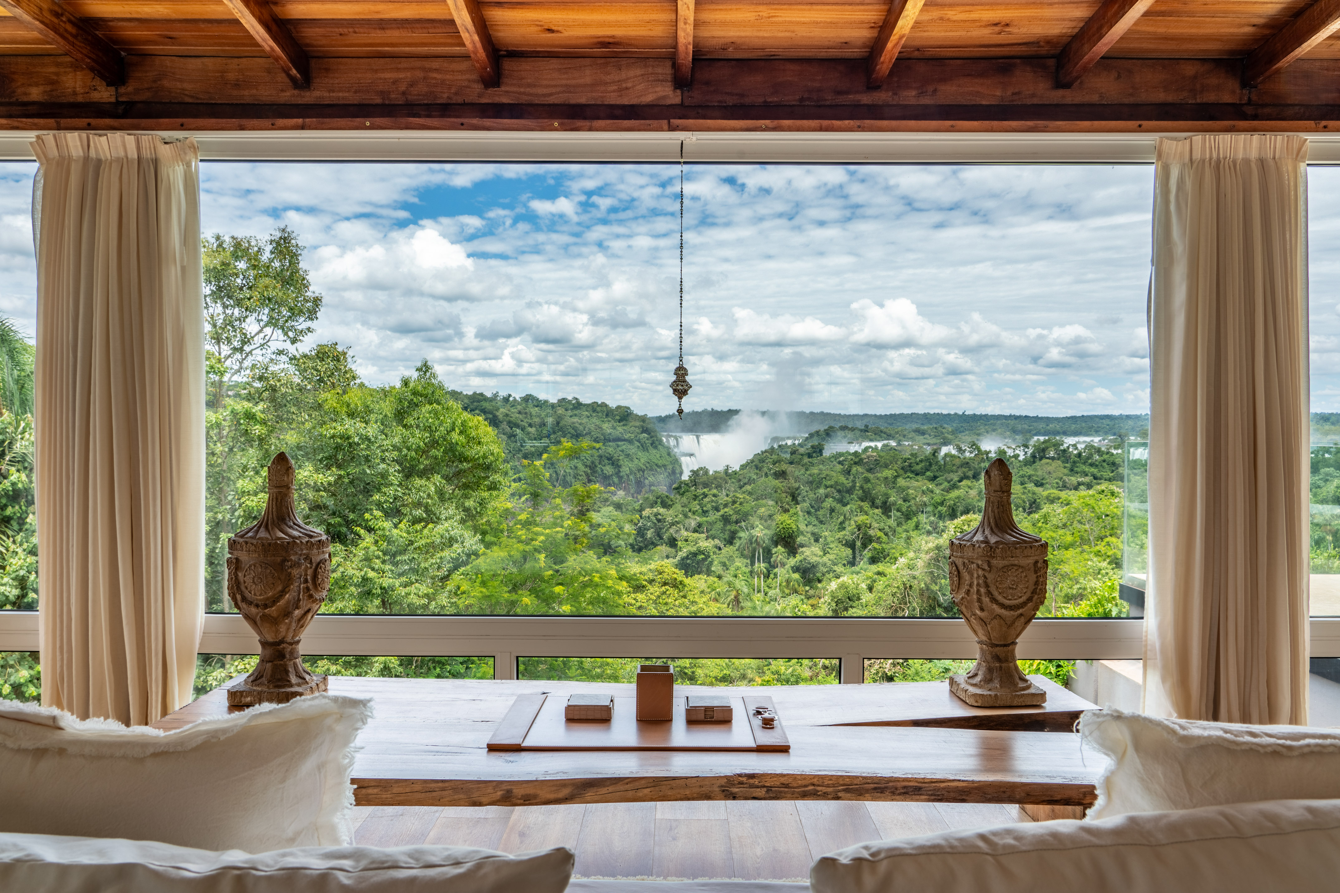 Wood interior with panoramic window framing waterfalls and lush rainforest.