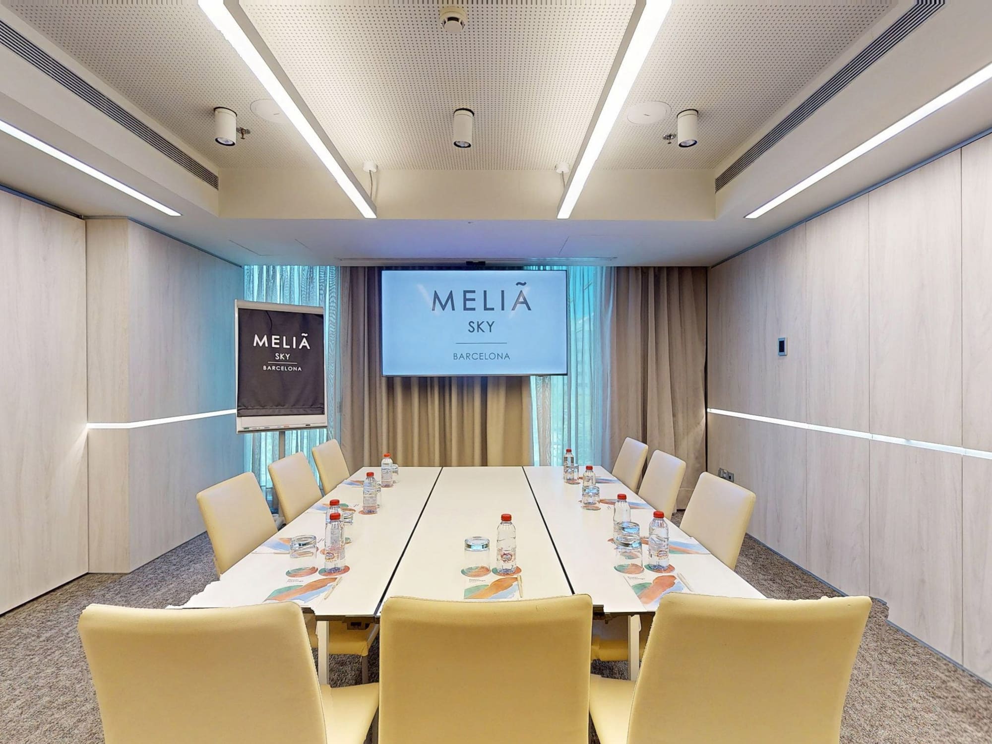 Modern Melia Sky Barcelona meeting room with conference table and display screen.